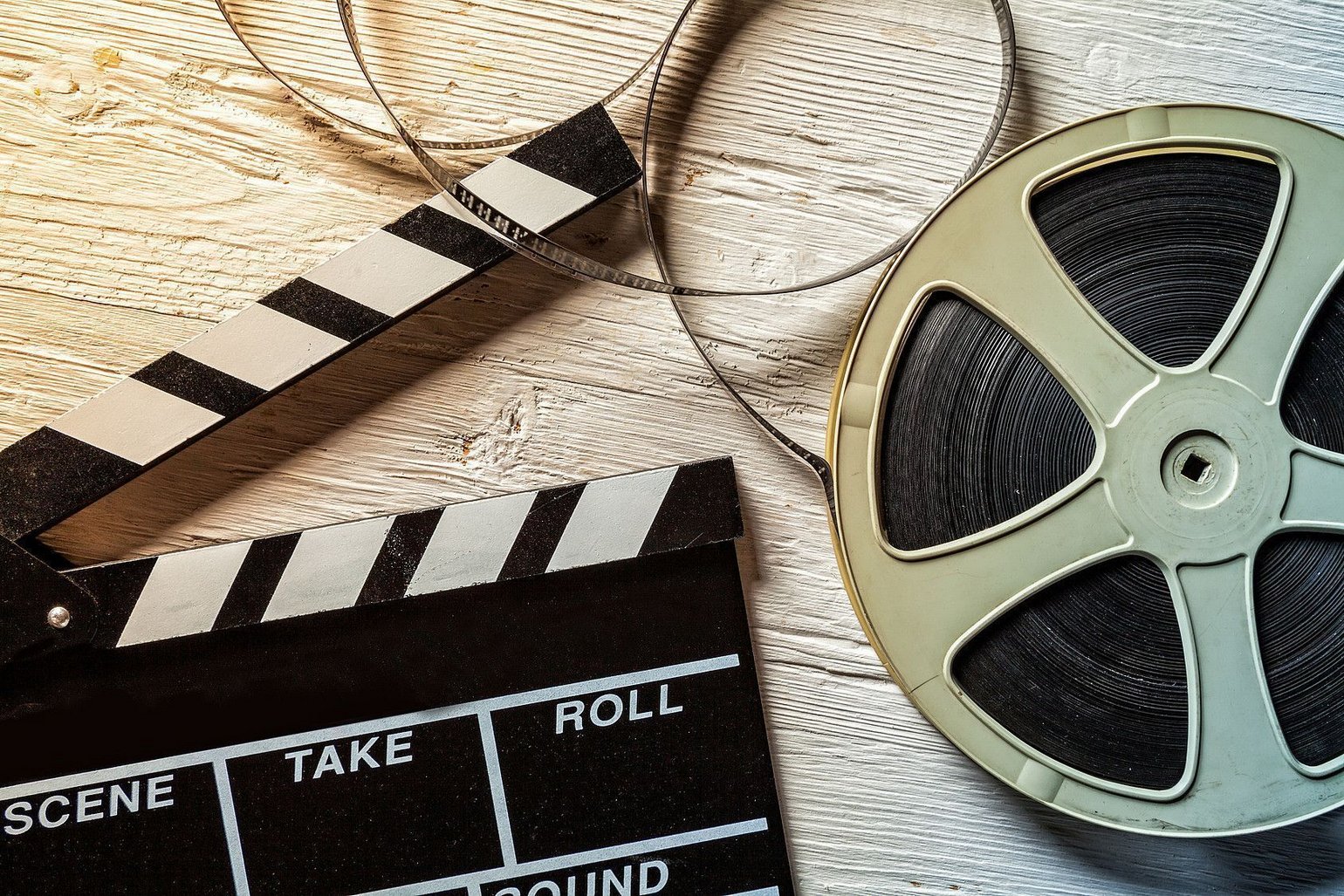 Filmklappe und Filmrolle auf einem hellen Holz Hintergrund