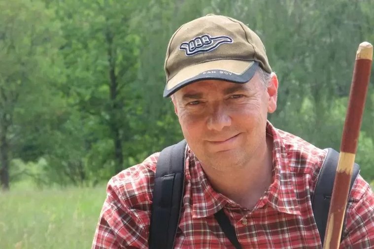 Wäller Wanderführer im Freien mit Wanderstock und lächelnd
