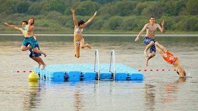 Sechs Personen springen fröhlich ins Wasser von einem Ponton