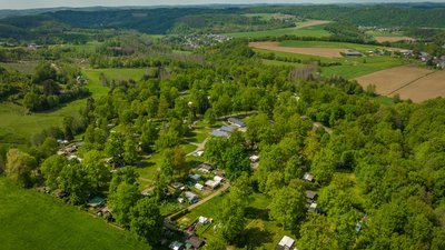 Grüne Landschaft mit Campingplätzen und Bäumen überblickt von oben