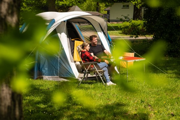 Zwei Personen entspannen vor einem Zelt auf einem Campingplatz