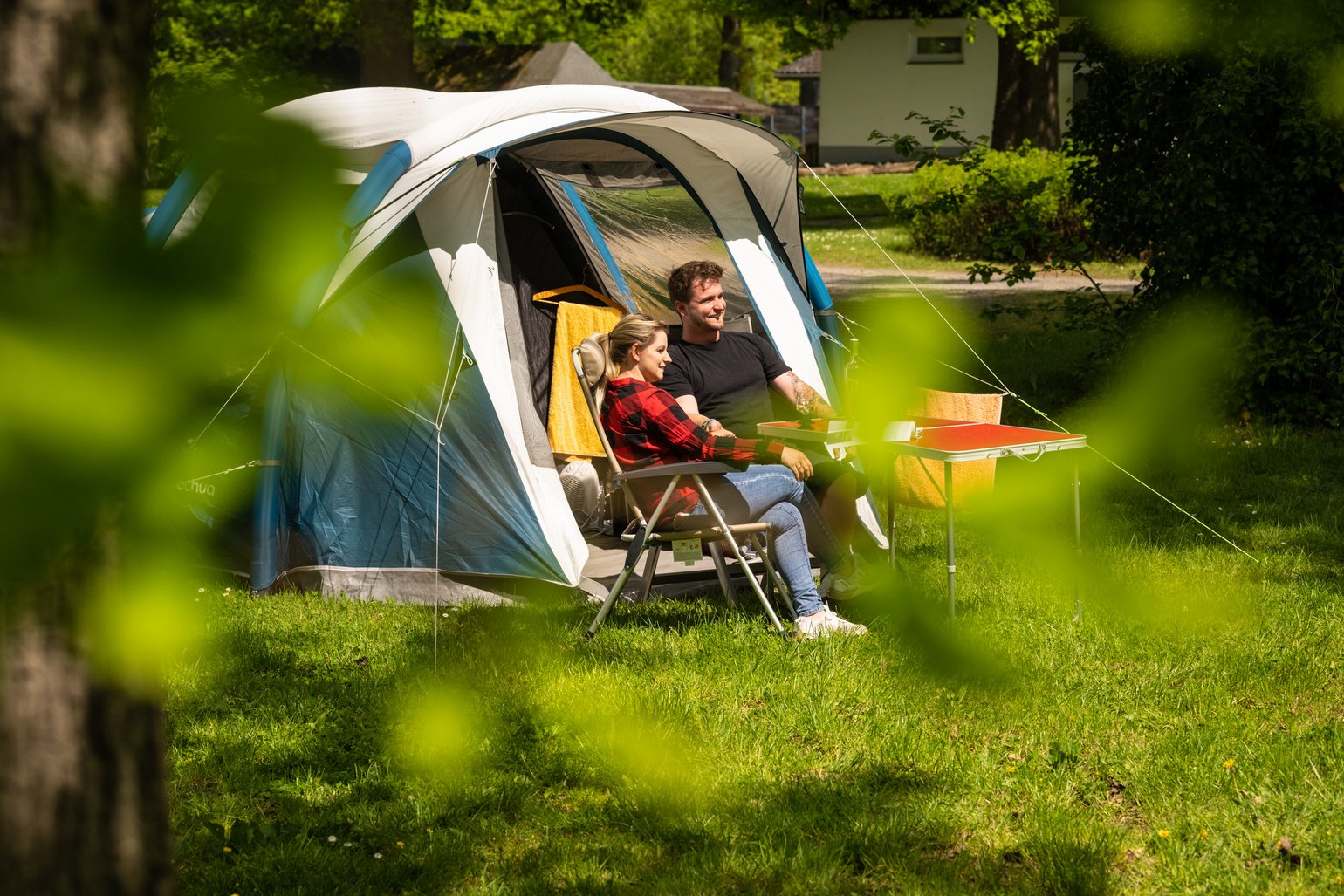 Zwei Personen entspannen vor einem Zelt auf einem Campingplatz