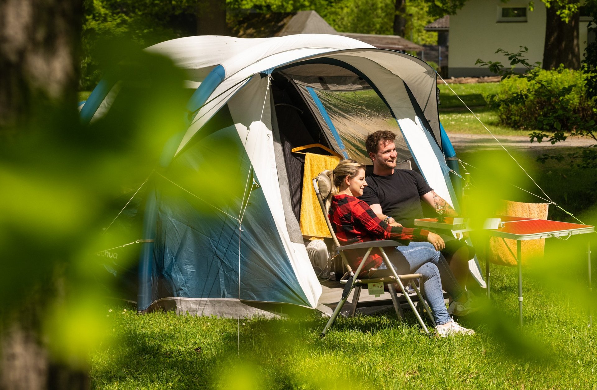 Zwei Personen entspannen vor einem Zelt auf einem Campingplatz