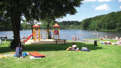 Familien und Kinder genießen einen Tag am See mit Spielplatz und Wiese