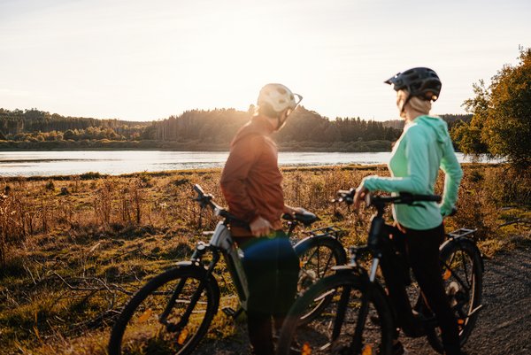 Zwei Radfahrer genießen den Blick auf das Wasser bei Sonnenuntergang