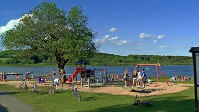 Familien genießen einen Spielplatz und den See an einem sonnigen Tag