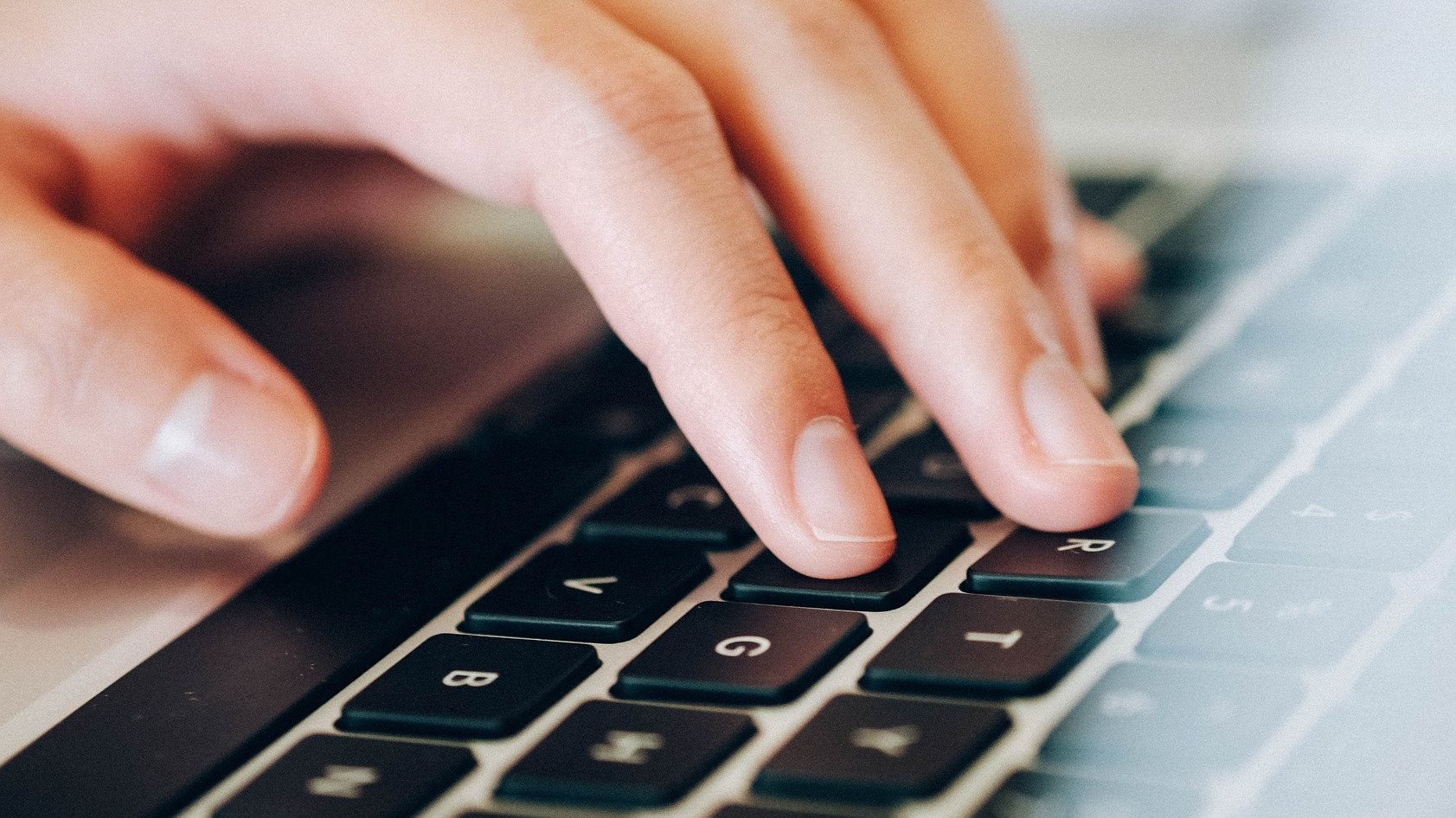 Eine Hand tippt auf einer Laptop-Tastatur