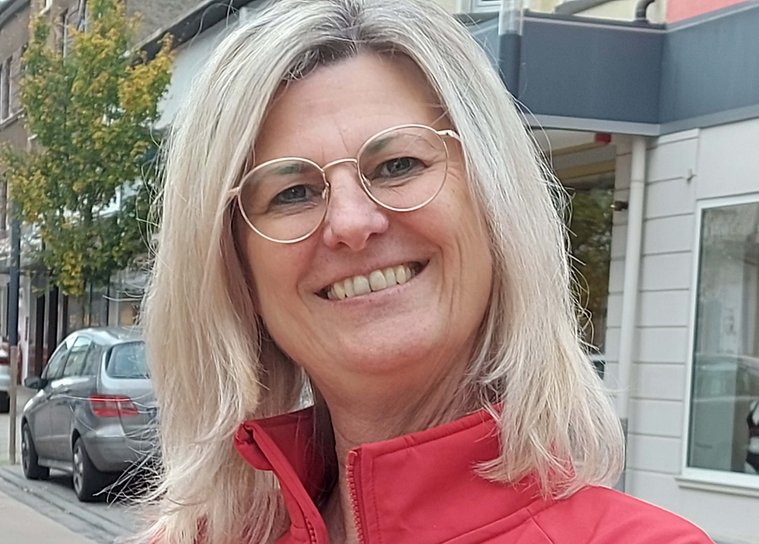 Lächelnde Frau in roter Jacke vor einer Stadtansicht