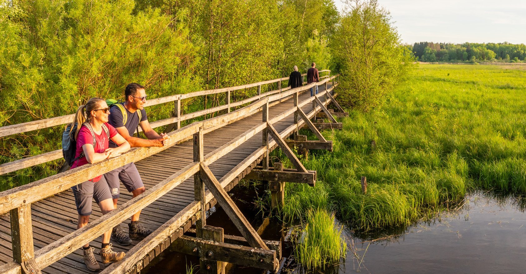 Zwei Personen beobachten die Landschaft an einem ruhigen Gewässer