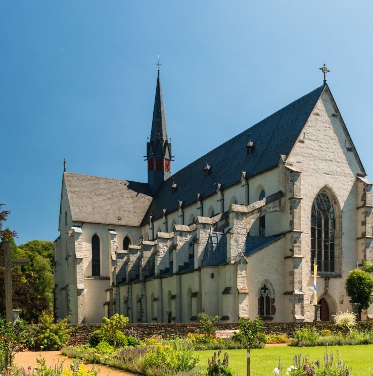 Friedlicher Garten mit bunten Blumen vor einer Kirche