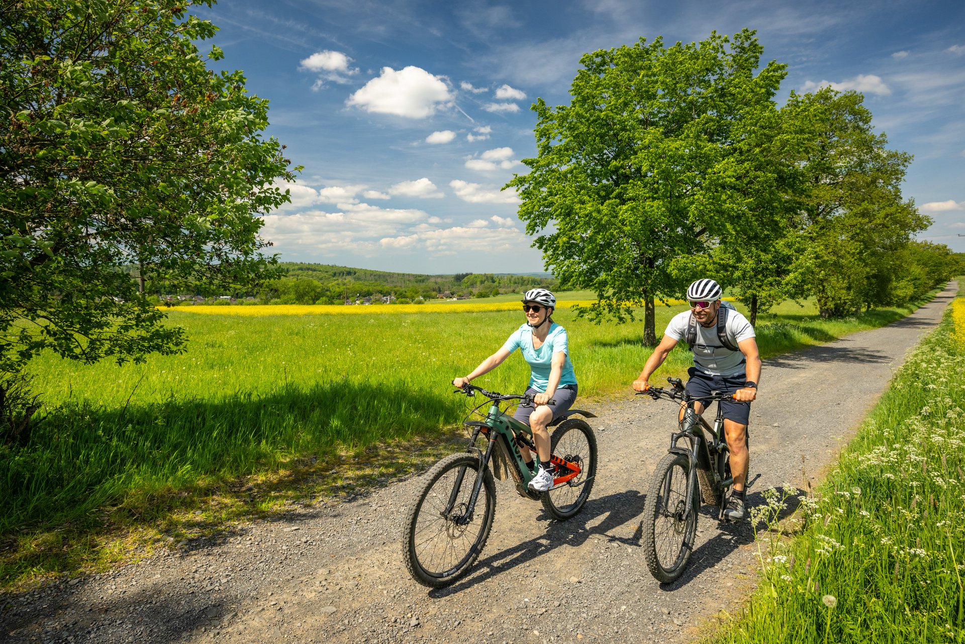 Zwei Radfahrer genießen eine Fahrt auf einem Feldweg bei sonnigem Wetter