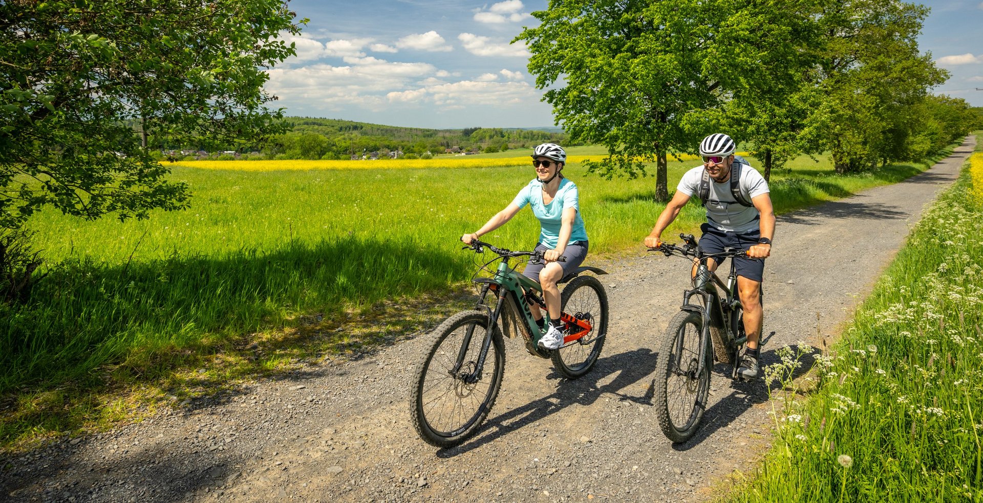 Zwei Radfahrer genießen eine Fahrt auf einem Feldweg bei sonnigem Wetter