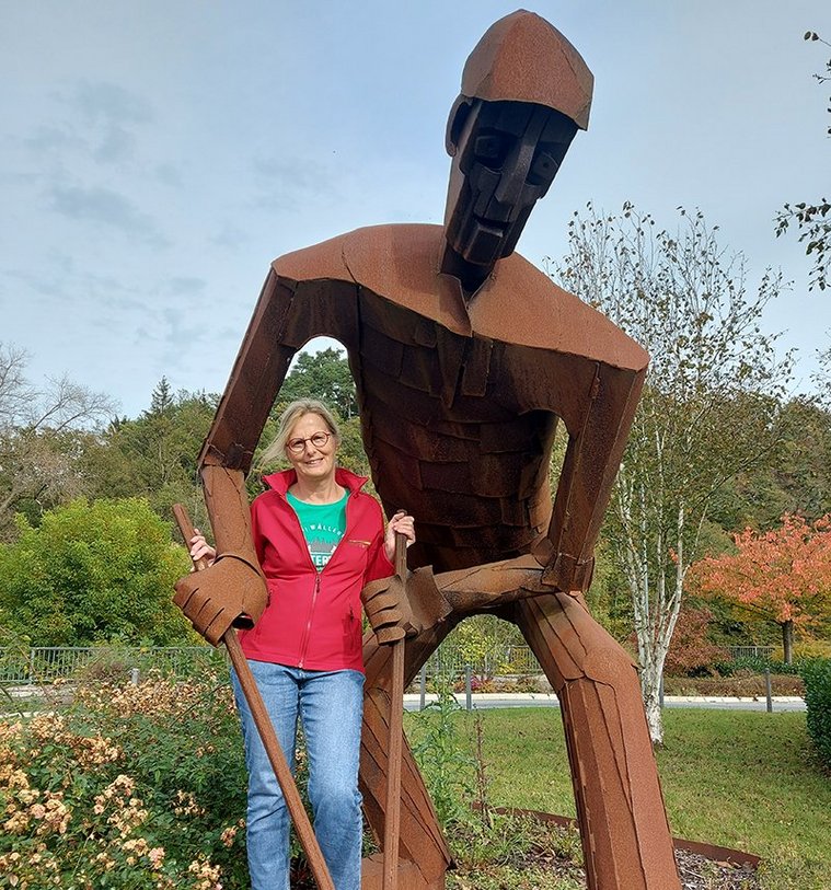 Wanderführerin posiert neben einer beeindruckenden Eisen-Skulptur