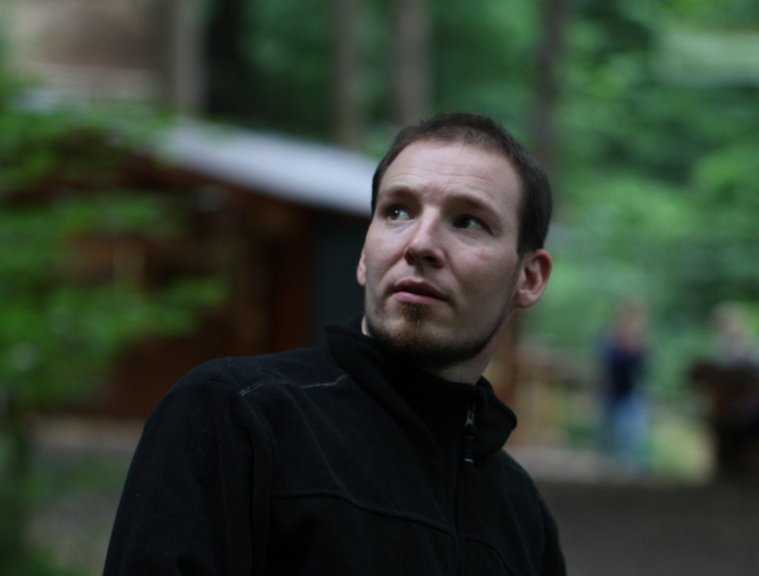 Mann in Jacke steht in der Natur, Blick nachdenklich