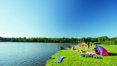 Menschen entspannen am Ufer eines ruhigen Sees in der Sonne