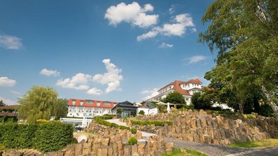 Hotelgebäude umgeben von Natur und Steinmauer bei blauem Himmel