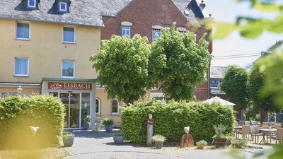 Gemütliche Eisdiele EISBACH mit Bäumen und Sitzgelegenheiten im Freien