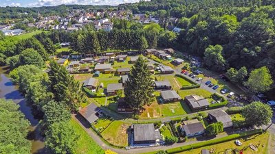 Panoramablick auf Ferienhütten umgeben von Bäumen und einem Fluss