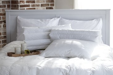 Helles Bett mit weißen Kissen und einem Tablett mit Kerzen