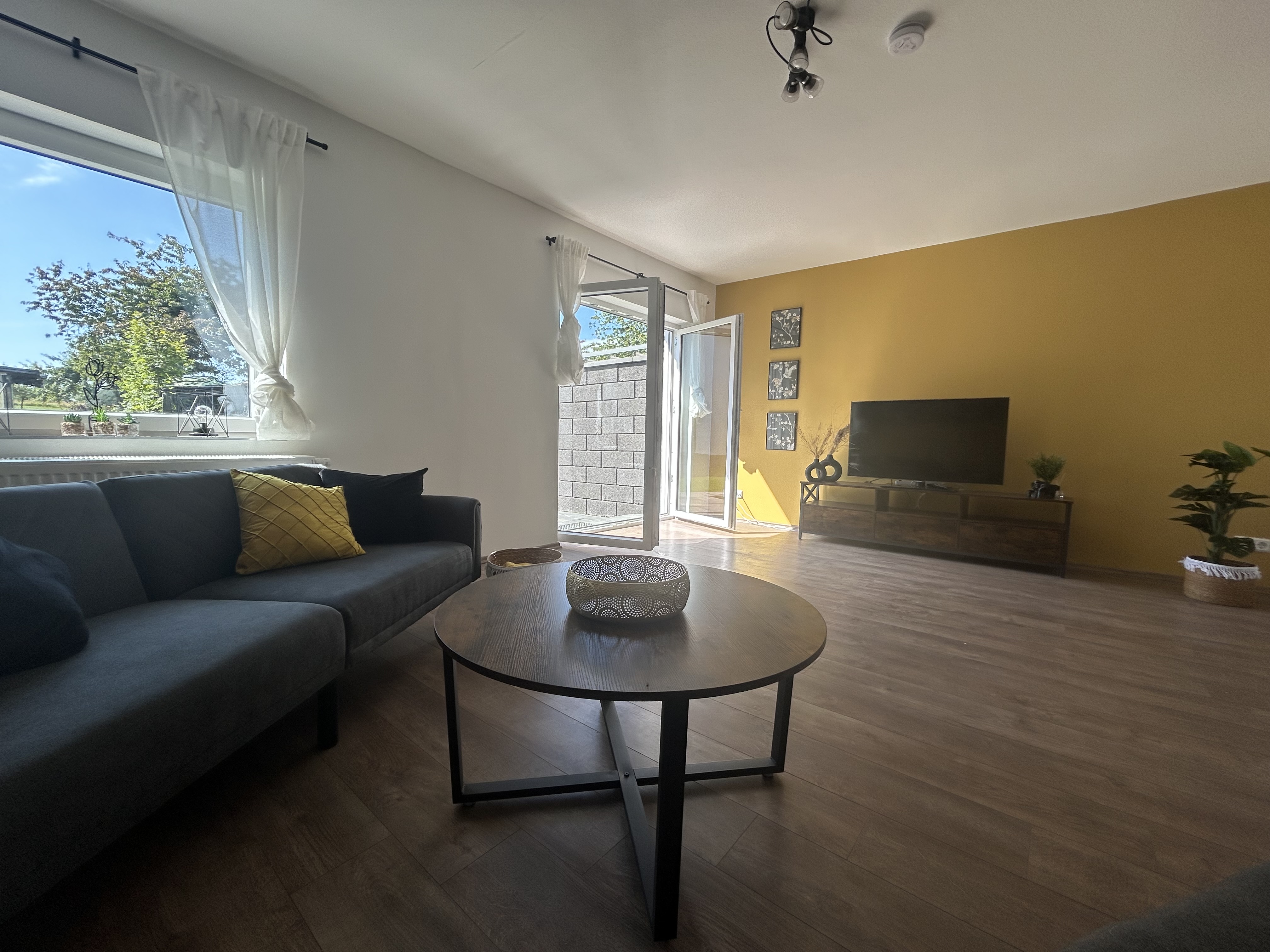 Helles Wohnzimmer mit Sofa, Couchtisch und TV-Schrank