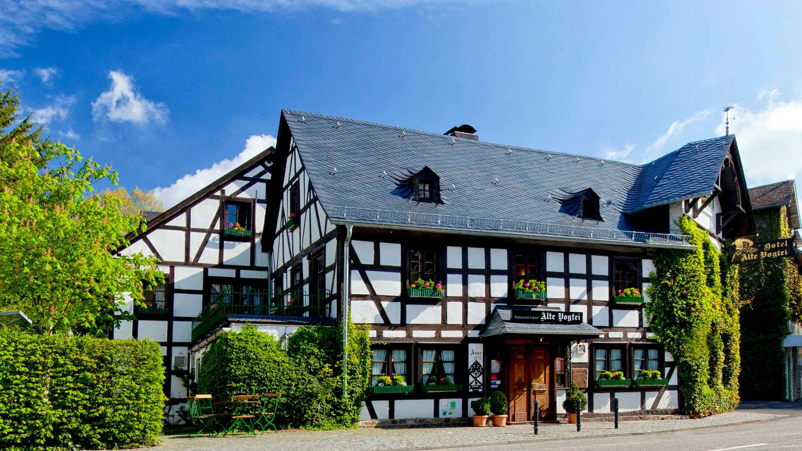 Fachwerkhaus mit grünem Pflanzenbewuchs und klarem Himmel