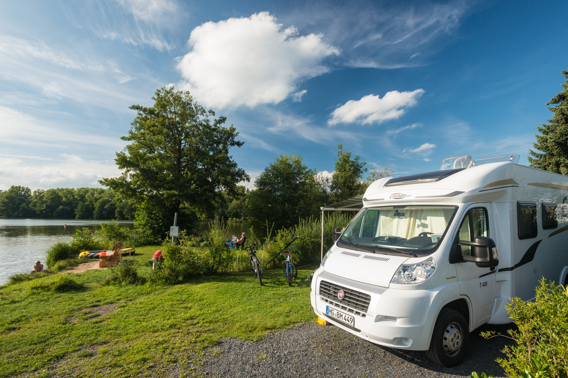 Wohnmobil-Szene am See mit grünem Umfeld und Freizeitgestaltungen