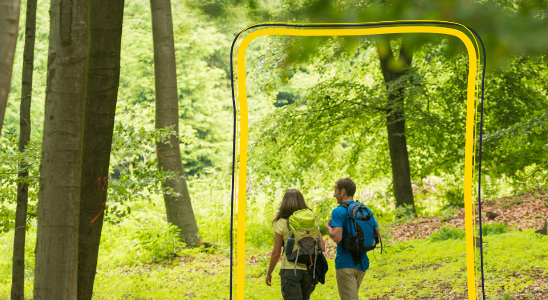 Zwei Wanderer gehen durch einen Wald mit einem gelben Rahmen